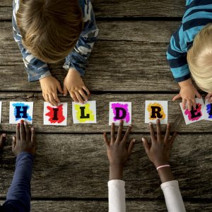 Top View Of Four Children Of Mixed Races Touching A Word Childre