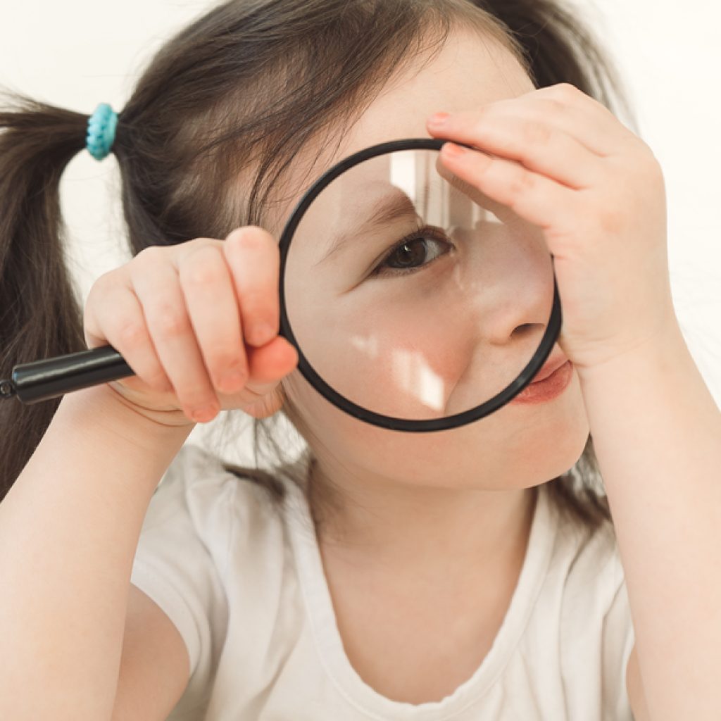 little girl plays a detective. a child examines something throug