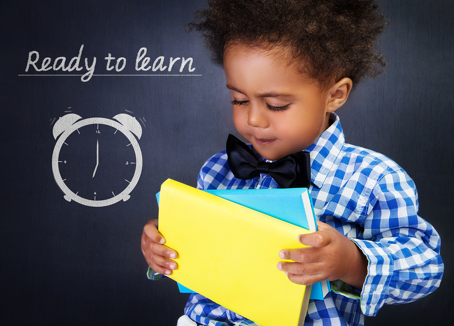 cute african american boy with books in hands on blackboard back