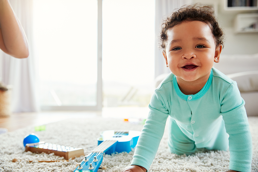 happy mixed race toddler boy crawling in sitting room